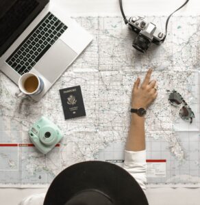 woman relaxed drinking coffee looking at a laptop with a passport camera and map. Stress free vacation planning concept
